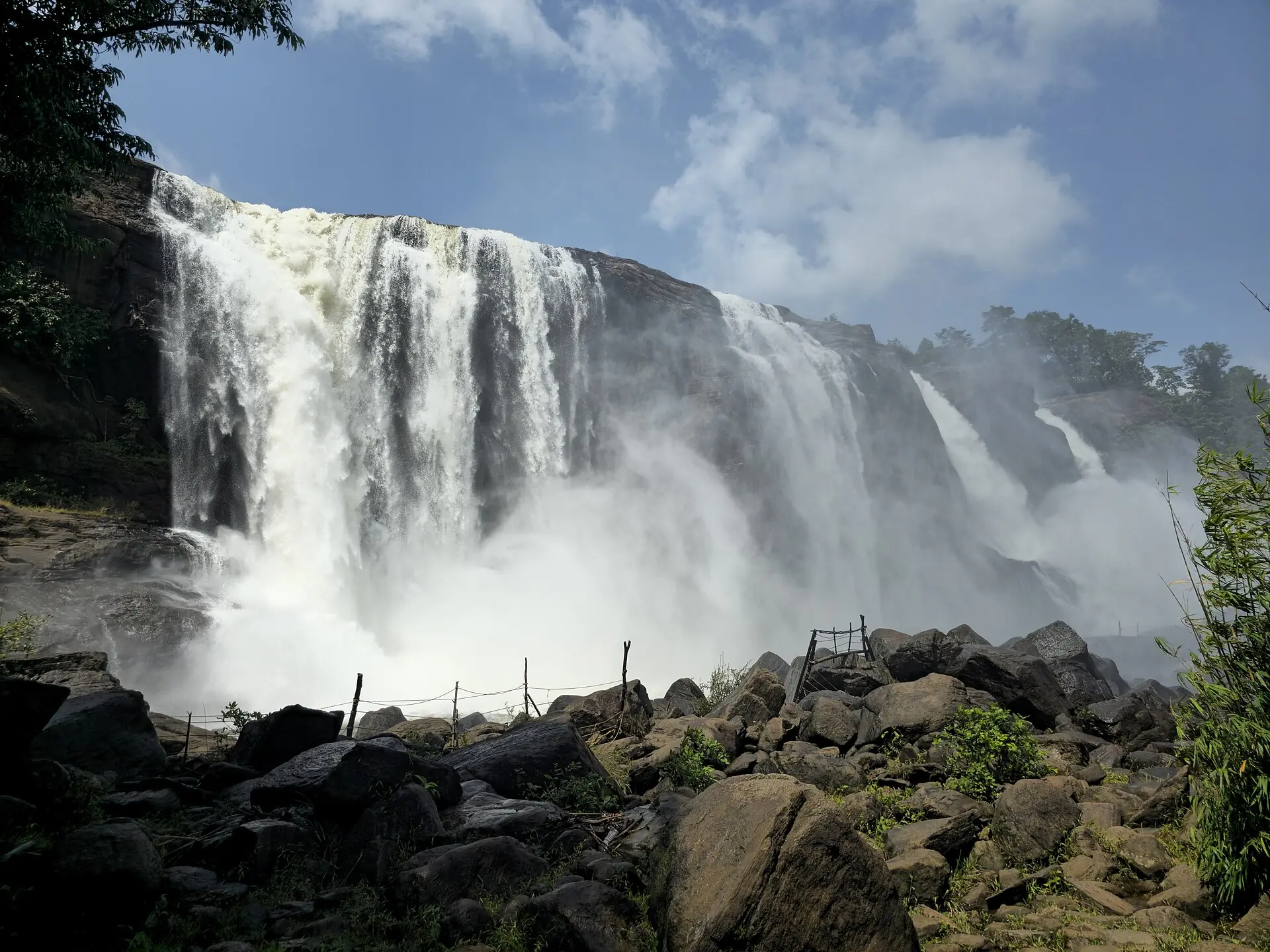 Athirappilly Falls pouring over a wide rock face into the river below